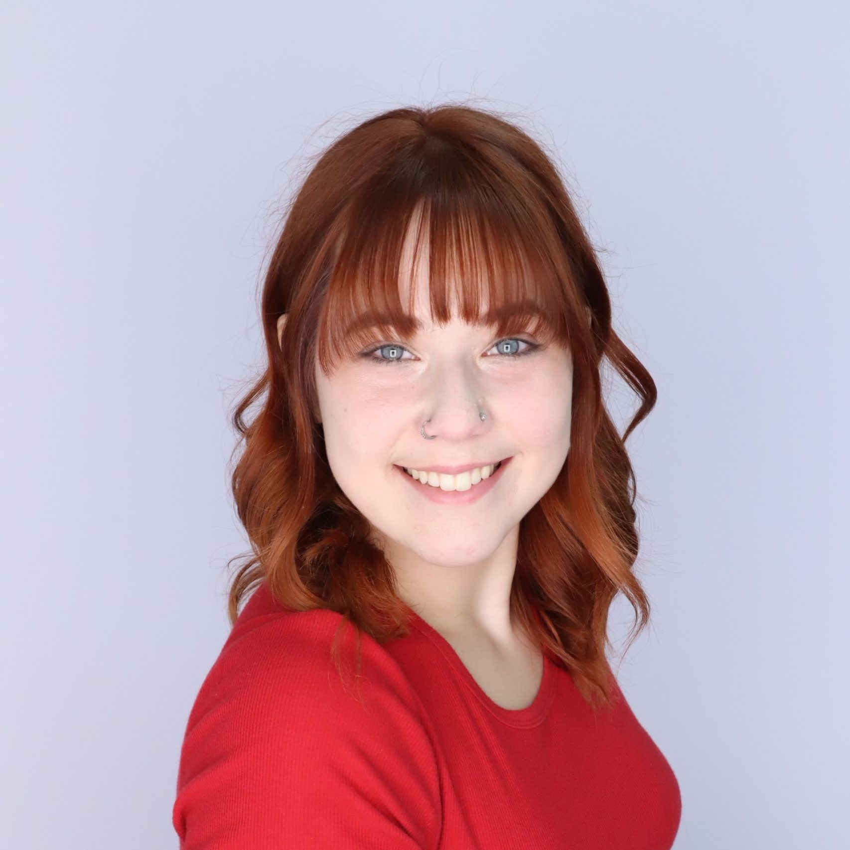 A photo of Bianca smiling wearing a read shirt.
